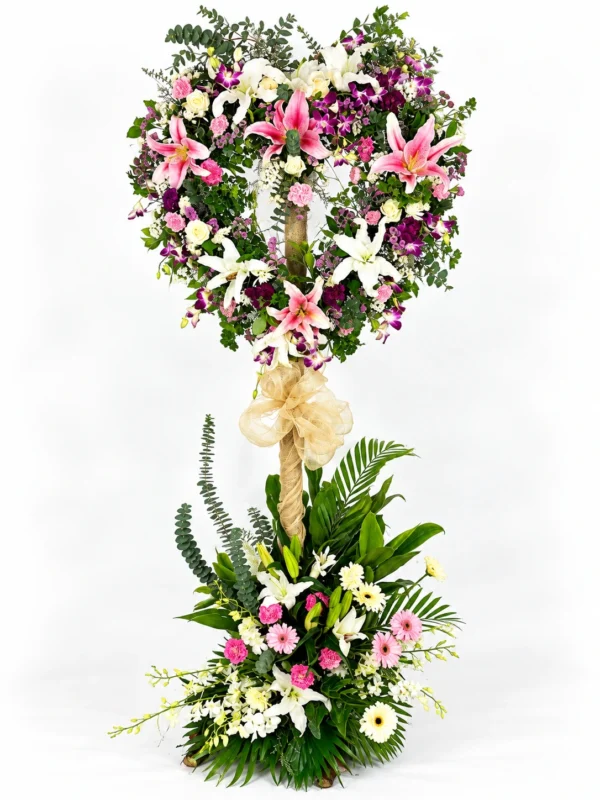 Beloved pink lily funeral heart stand with white lilies, carnations, orchids and a flower base