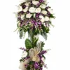 White anthurium and purple dendrobium orchid two-layer funeral stand with eucalyptus, tropical leaves and a cream abaca bow